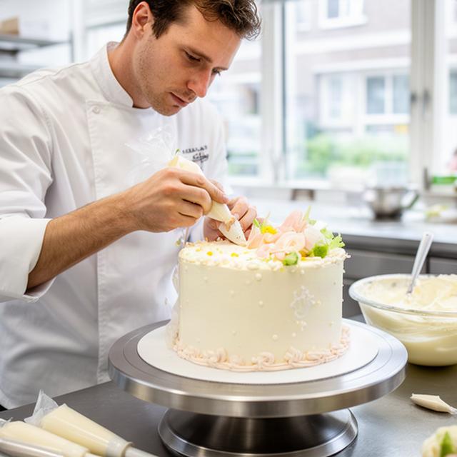 Patissier aan het werk met een gedecoreerde feesttaart in de lichte bakkerijkeuken van Heerlen